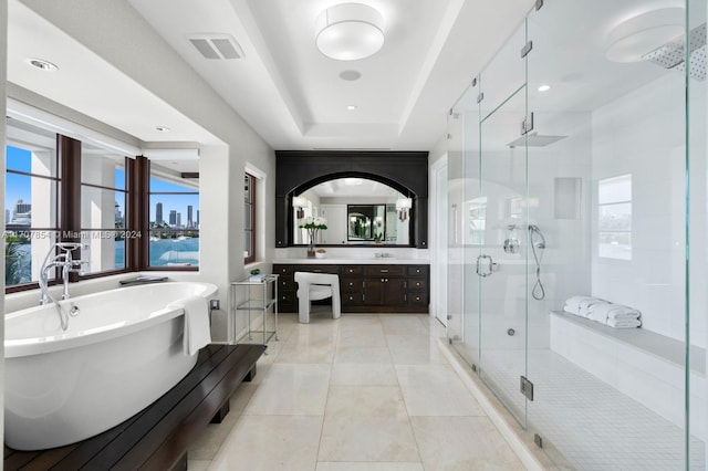 bathroom featuring plus walk in shower, vanity, a tray ceiling, and tile patterned floors