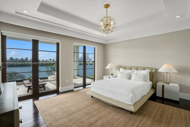 bedroom with access to exterior, dark hardwood / wood-style flooring, a water view, and multiple windows