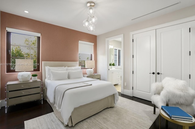 bedroom with ensuite bath, a closet, and dark wood-type flooring