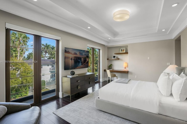 bedroom with access to outside, multiple windows, a raised ceiling, and dark hardwood / wood-style floors