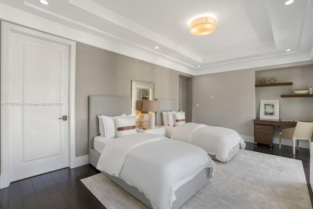 bedroom featuring a raised ceiling and dark hardwood / wood-style flooring