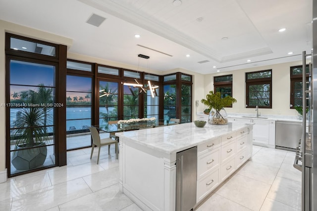 kitchen featuring white cabinetry, sink, light stone countertops, decorative light fixtures, and a kitchen island