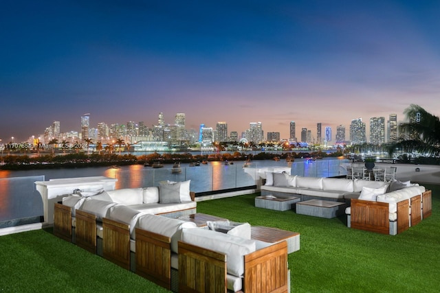 view of dock with an outdoor hangout area, a water view, and a lawn