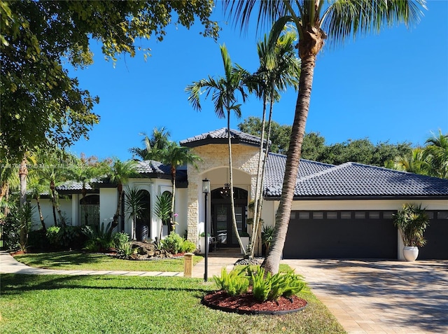 mediterranean / spanish house featuring a garage and a front lawn