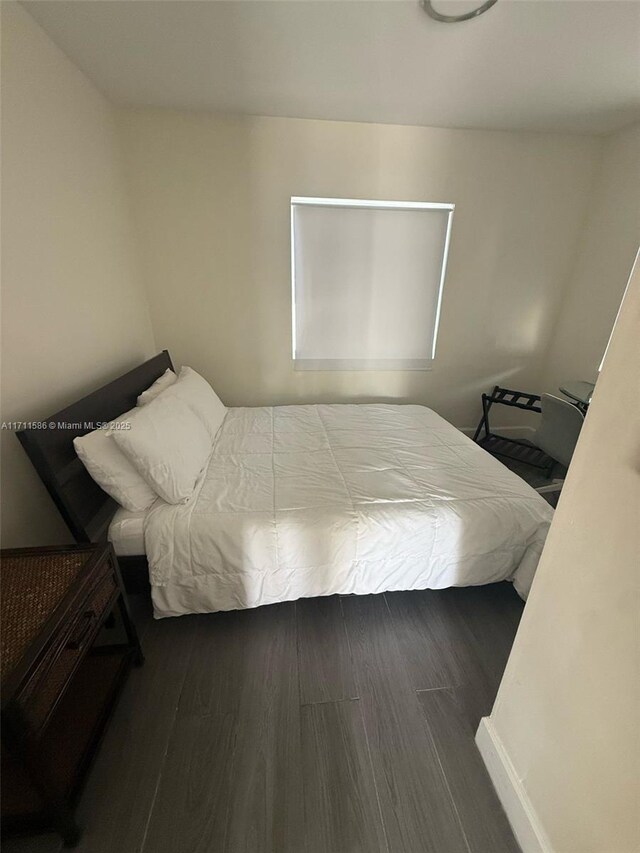 bedroom with ensuite bath and dark hardwood / wood-style flooring