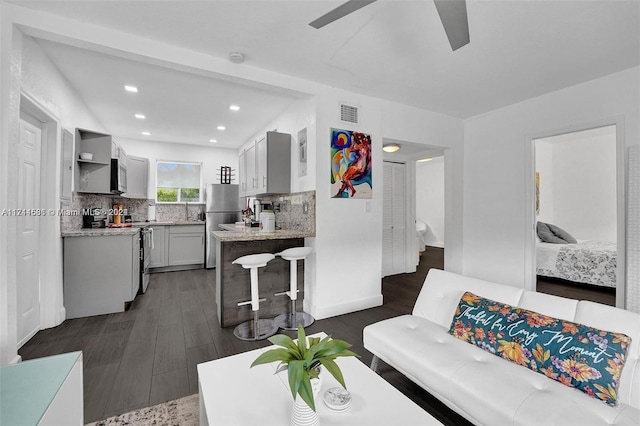 living room featuring ceiling fan and dark hardwood / wood-style flooring