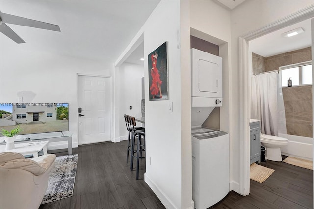 corridor with dark hardwood / wood-style flooring and stacked washer and dryer