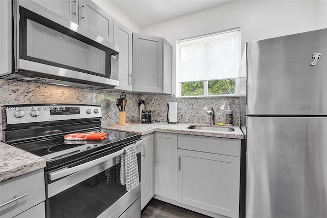 kitchen featuring dark wood-type flooring, sink, gray cabinets, appliances with stainless steel finishes, and tasteful backsplash