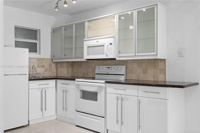 kitchen with white appliances, white cabinets, sink, light tile patterned floors, and tasteful backsplash