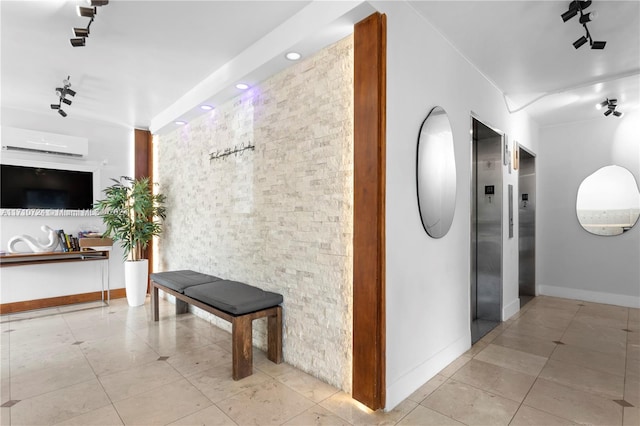 hallway with an AC wall unit, elevator, light tile patterned floors, and track lighting