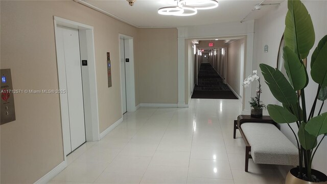 hallway with tile patterned flooring, stairway, elevator, and baseboards
