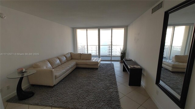 living room featuring a wall of windows, visible vents, a wealth of natural light, and light tile patterned flooring
