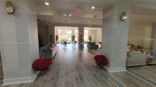 corridor featuring visible vents, a paneled ceiling, baseboards, and wood finished floors