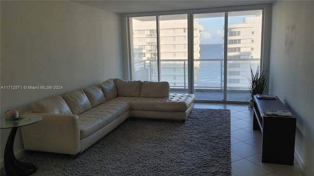 living room with a water view, tile patterned floors, and a wall of windows