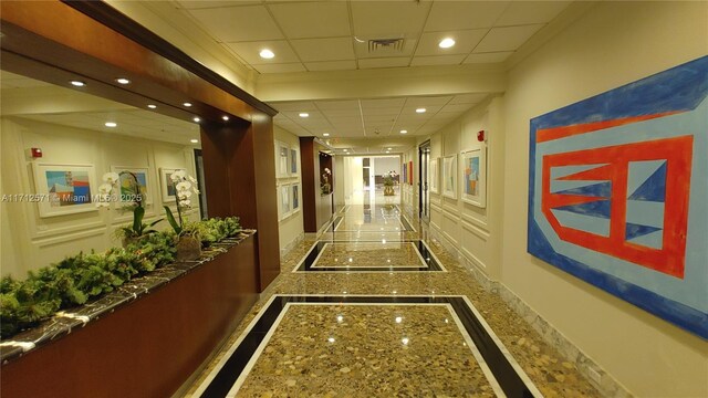 hall with granite finish floor, visible vents, recessed lighting, and a drop ceiling