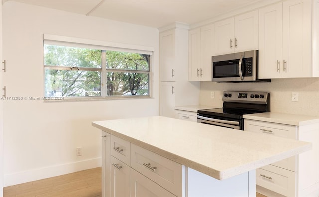 kitchen with white cabinets, a center island, appliances with stainless steel finishes, and light hardwood / wood-style flooring