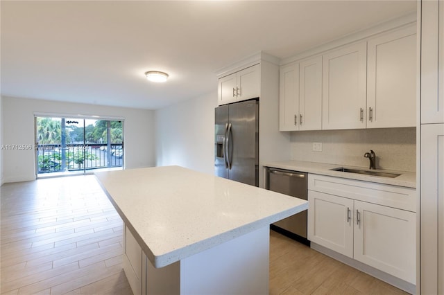 kitchen featuring white cabinetry, sink, stainless steel appliances, light hardwood / wood-style flooring, and a kitchen island