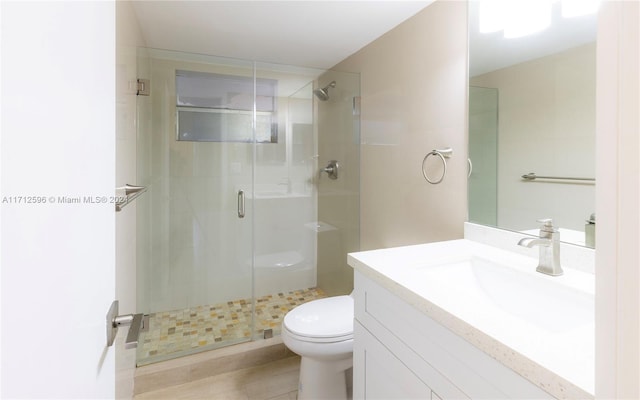 bathroom featuring tile patterned flooring, vanity, toilet, and a shower with door