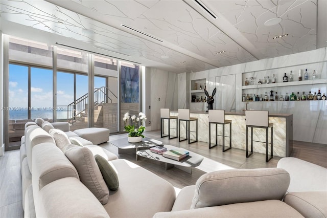 living room featuring bar area, a water view, and light hardwood / wood-style flooring