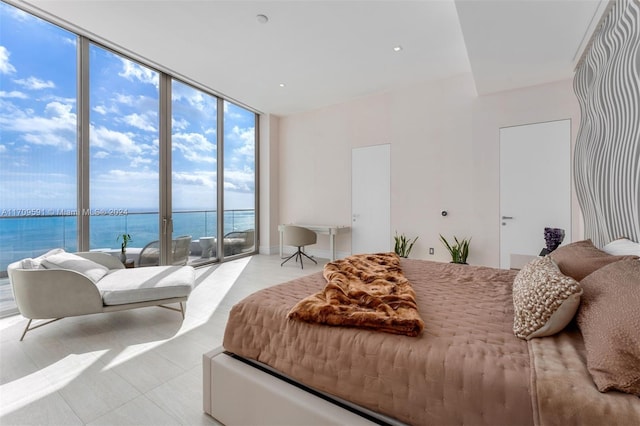 bedroom featuring floor to ceiling windows, a water view, and access to exterior