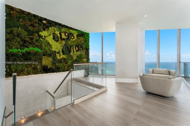 unfurnished living room featuring floor to ceiling windows, a water view, and light hardwood / wood-style floors