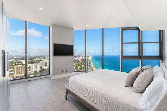 bedroom featuring multiple windows, light hardwood / wood-style flooring, and floor to ceiling windows