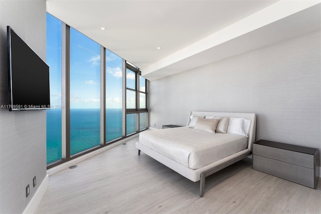 bedroom featuring a wall of windows and light hardwood / wood-style flooring