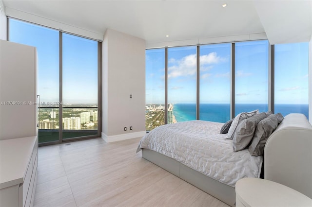 bedroom with floor to ceiling windows, a water view, and multiple windows