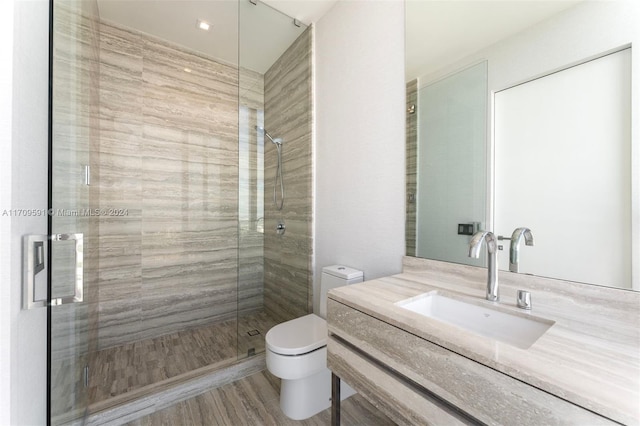 bathroom with vanity, toilet, wood-type flooring, and a shower with door