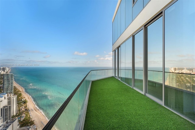 balcony with a water view and a view of the beach