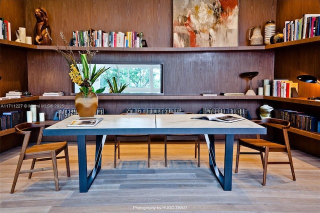 dining area with wood-type flooring, built in desk, and wooden walls