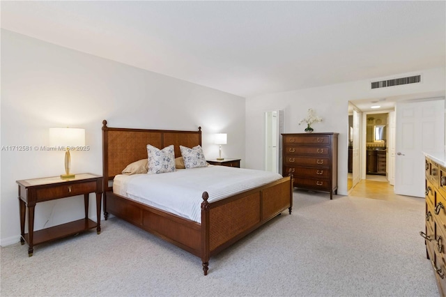 bedroom featuring visible vents, ensuite bath, light carpet, and baseboards