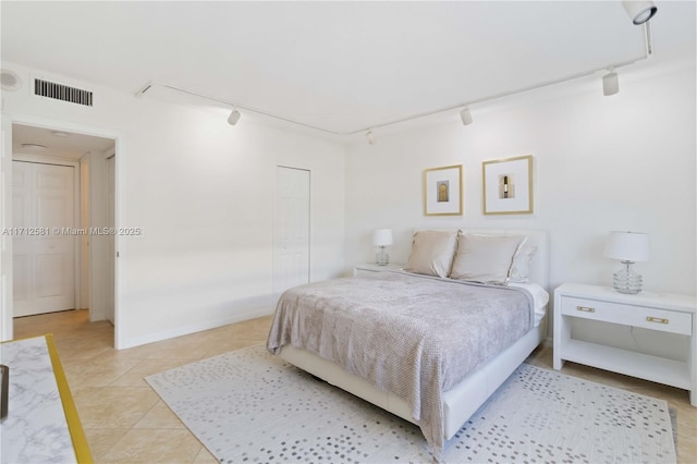 bedroom with track lighting, a closet, and light tile patterned flooring