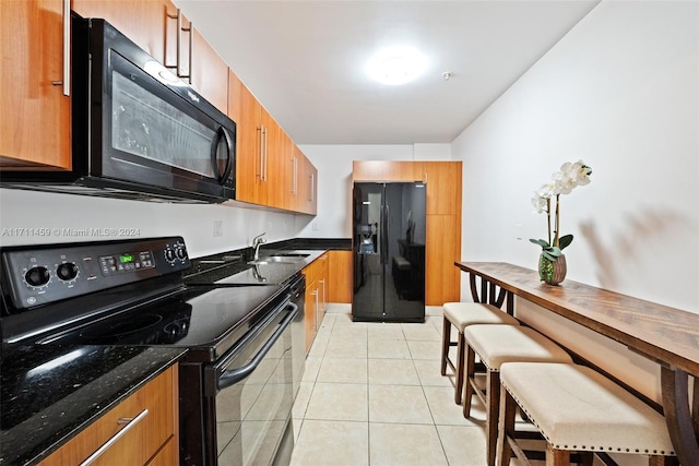 kitchen featuring sink, light tile patterned floors, and black appliances