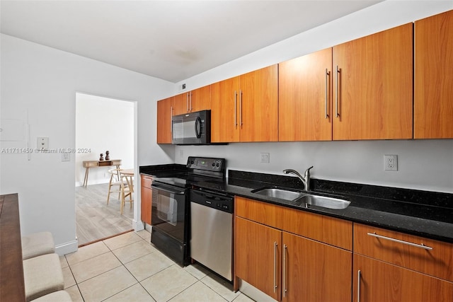 kitchen featuring appliances with stainless steel finishes, light hardwood / wood-style floors, dark stone counters, and sink