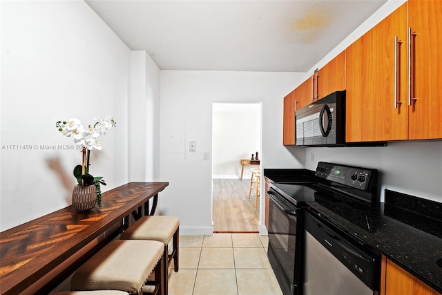 kitchen featuring dark stone countertops, electric range, dishwasher, and light hardwood / wood-style flooring