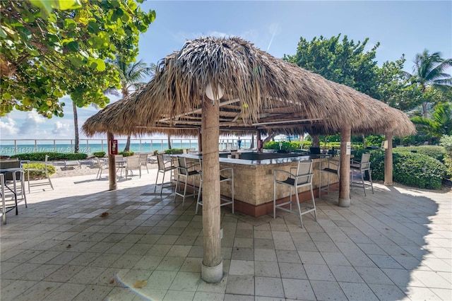 view of patio / terrace featuring exterior bar, a gazebo, and a water view