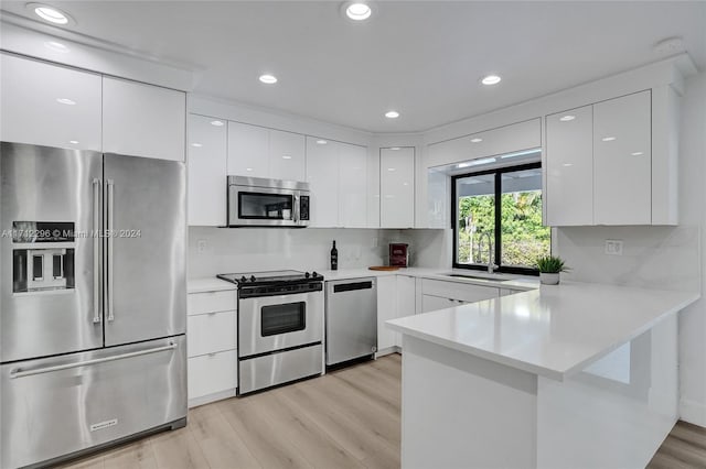 kitchen with kitchen peninsula, white cabinetry, sink, and stainless steel appliances