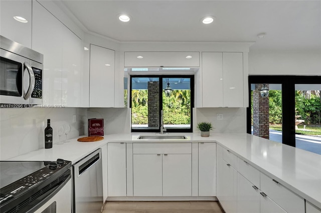 kitchen featuring white cabinets, stainless steel appliances, plenty of natural light, and sink