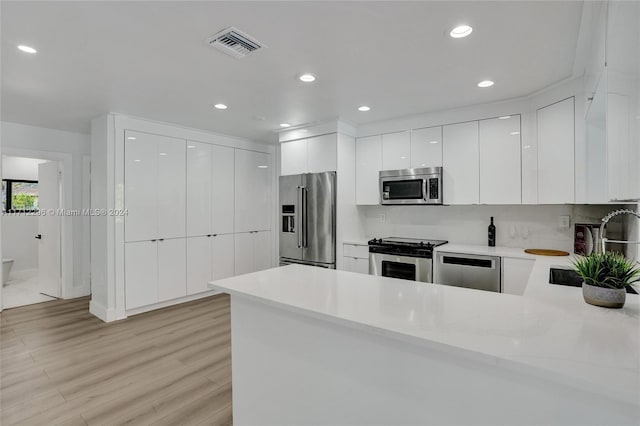 kitchen featuring kitchen peninsula, white cabinetry, sink, and stainless steel appliances