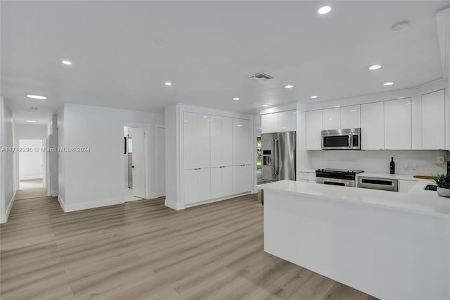 kitchen featuring kitchen peninsula, white cabinets, light hardwood / wood-style floors, and appliances with stainless steel finishes