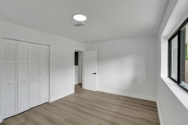 unfurnished bedroom with a closet and light wood-type flooring