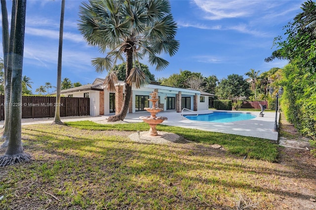 rear view of house with a fenced in pool and a yard