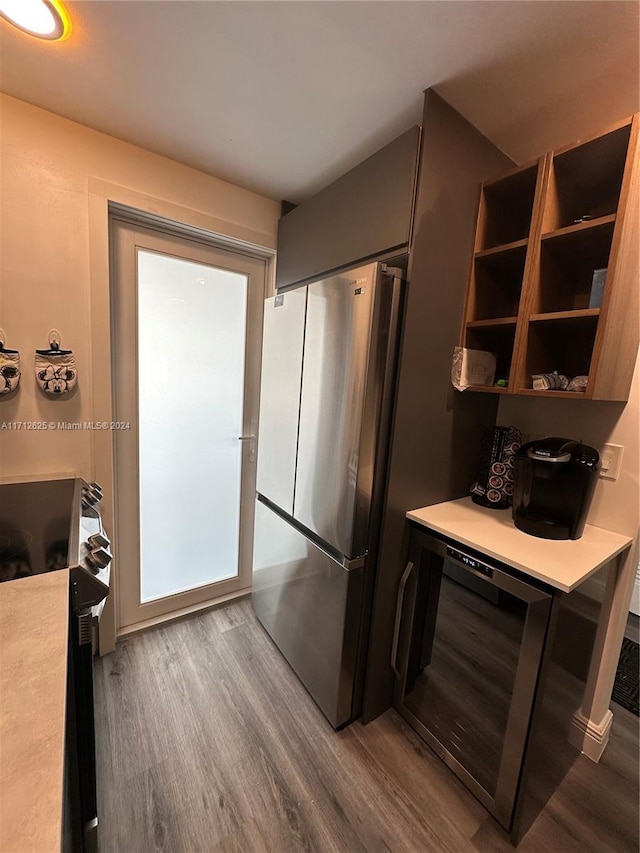 kitchen featuring hardwood / wood-style flooring, beverage cooler, stove, and stainless steel refrigerator