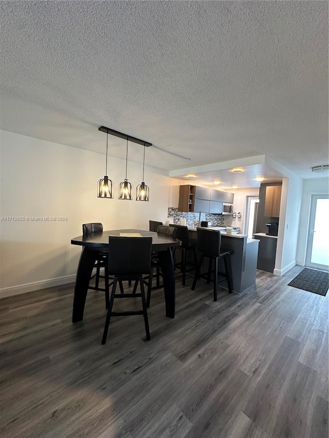 dining room with a textured ceiling and dark hardwood / wood-style floors