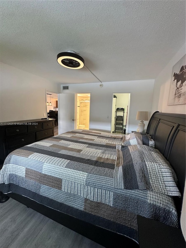 bedroom featuring hardwood / wood-style floors, ensuite bathroom, and a textured ceiling