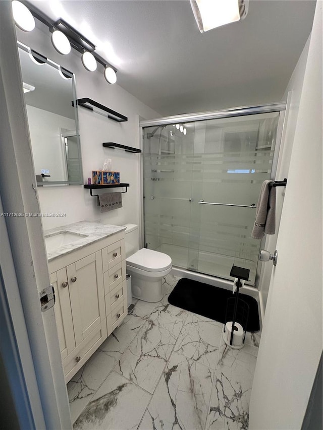 bathroom featuring vanity, toilet, and a shower with door