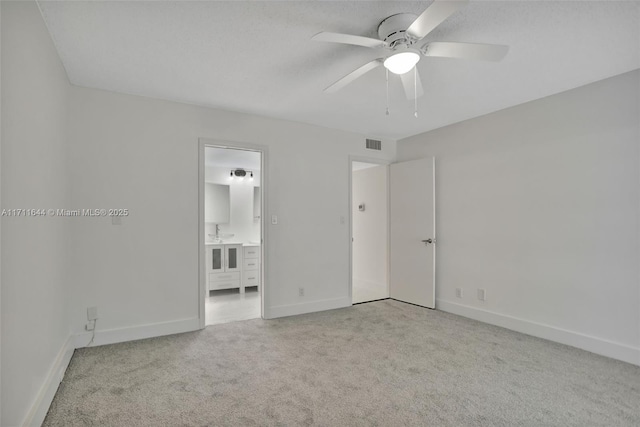 unfurnished bedroom featuring ceiling fan, light carpet, and ensuite bath