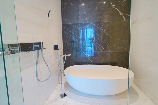 bathroom with a bath, tile patterned floors, and tile walls