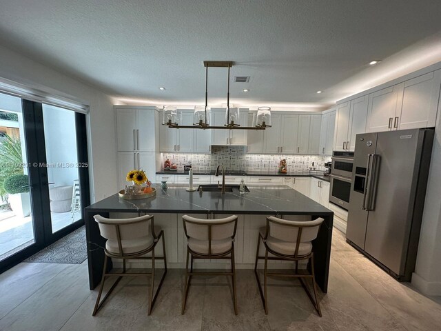 kitchen with a center island with sink, white cabinetry, and appliances with stainless steel finishes